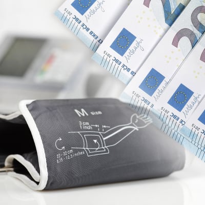 En blodtrycksmätare och ett antal 20 eurossedlar i en illustrativ bild.