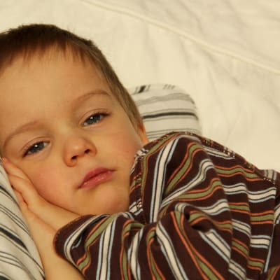 Förkyld 3-årigpojke vilar på soffa.