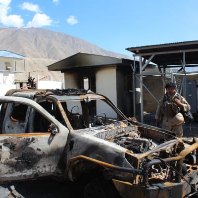 En afghansk polis inspekterar en polisbil som tänts eld på under en attack mot en vägspärr i nordöstra Afghanistan.