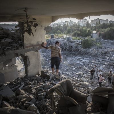 En palestinsk man tittar på sitt sönderbombade hur i Gaza.