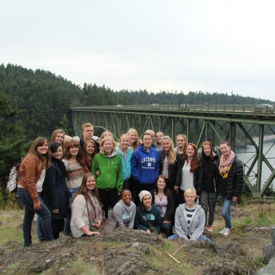 En grupp finländska elever och vänelever uppställda framför en bro i La Conner.