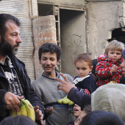 Rami Adham delar ut bananer åt barnen i Aleppo.