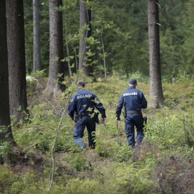 Kaksi poliisia kävelee maastossa.