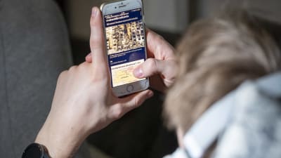 En person läser Helsingin sanomats nyheter på telefonen.