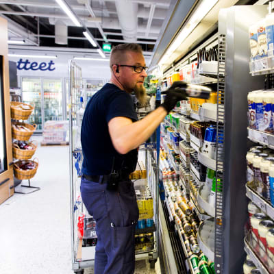 Työntelijä hyllyttää alkoholijuomia K- supermarket Kampissa, Helsingissä.