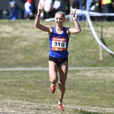 Nina Chydenius springer med fingrarna mot luften.