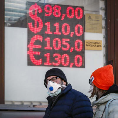 Människor går framför en valutaväxlingskontor i Moskva.