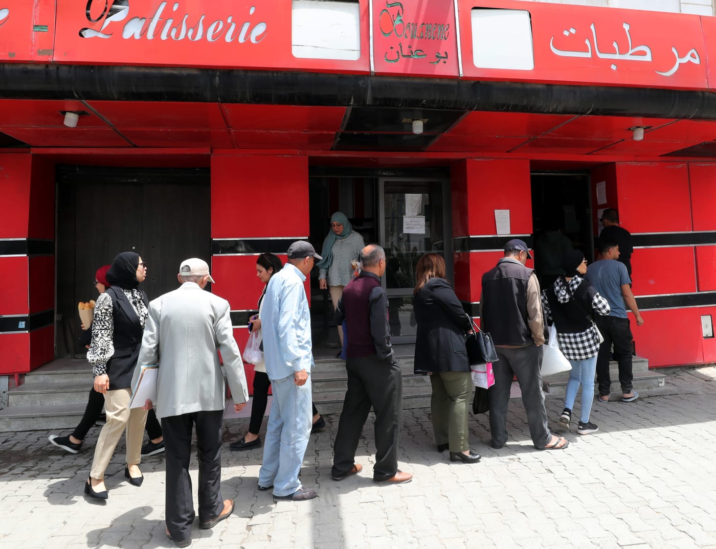 Tunisini in fila davanti a un panificio che produce pane sovvenzionato.