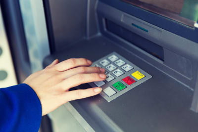 Hand knäpper in pinkod på bankautomat