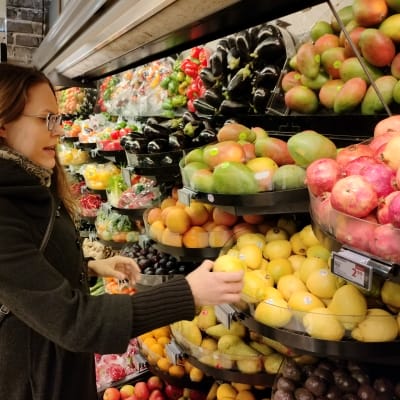 Näringsvetare Charlotta Hyttinen vid frukthyllan i en matbutik.