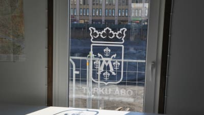 Åbo stads vapen klistrat på en glasdörr, i bakgrunden genom rutan skymtar torgparkeringsbygget.