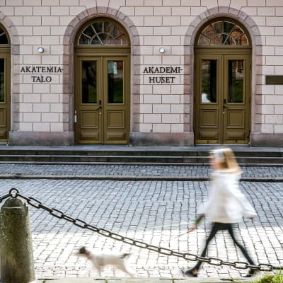 En flicka går med sin hund utanför Akademihuset i Åbo