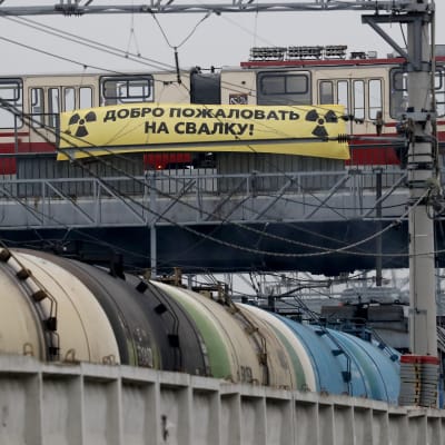 En spårvagn och en gul banner med texten "välkommen till skräpdumpen" på ryska.