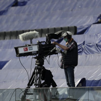 Kameramannen som filmar matchen mellan Eintracht Frankfurt och Borussia Mönchengladbach bär andningsskydd.