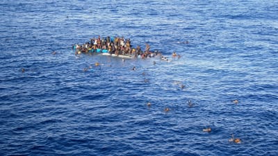 Flyktingar försöker simma i säkerhet från sjunkande båt.