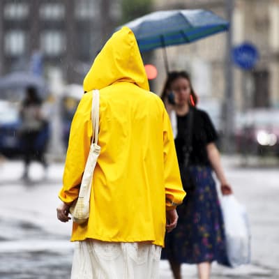 En person i en gul regnrock går på en regnig gata.