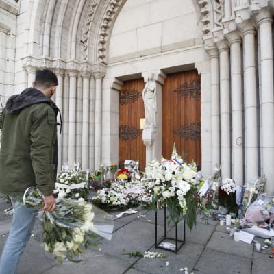 En man lägger en bukett utanför Notre-Dame-basilikan i Nice den 30 oktober 2020 till minne av offren i knivattacken.