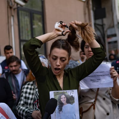 En iransk kvinna, som bor i Turkiet, klipper av sin hästsvans under en protest. 