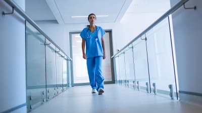 En sjukskötare fotograferad nerifrån medan hon går i en sjukhuskorridor.