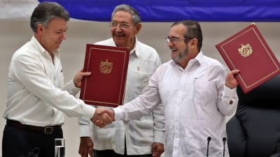 Colombias president Juan Manuel Santos och Farcledaren Timoleón Jiménez skakar hand framför Kubas president Raul Castro.