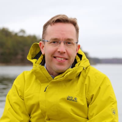 Ilari E. Sääksjjärvi istuu merenrannalla.