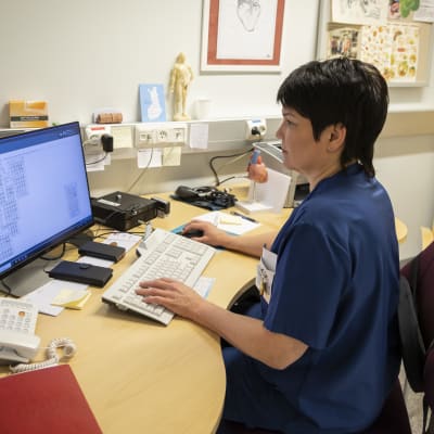 Sairaanhoitaja käyttää tietokonetta. 