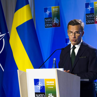 Ulf Kristersson håller presskonferens med Natos och Sveriges flagga i bakgrunden.