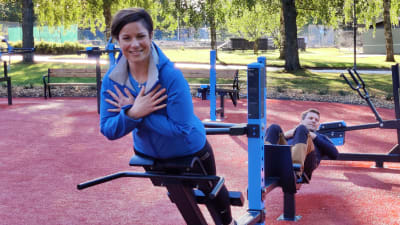 En kvinna och en man motionerar med redskap i en motionspark.