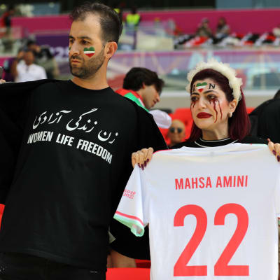 Mies ja nainen osoittivat mieltään Iranin hallintoa vastaan jalkapallon MM-kisojen katsomossa.