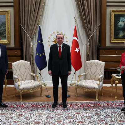 Europeiska rådets ordförande Charles Michel och kommissionens ordförande Ursula von der Leyen tillsammans med Turkiets president Erdogan. I bakgrunden syns EU:s och Turkiets flaggor, samt två stolar. 