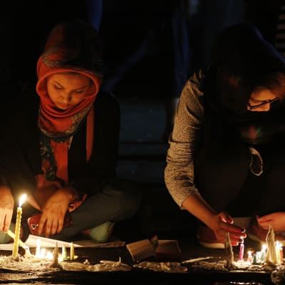 Två afghanska kvinnor tänder ljus under en minnesstund som ordnades för de som dödats i bombattacken i Kabul där minst 80 personer miste livet.