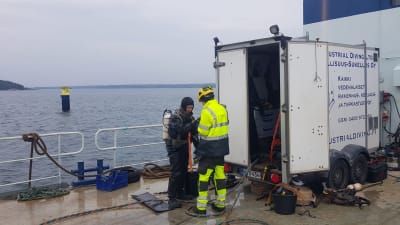 Dykare på ett fartyg som ska dyka ner till en sten som ska sprängas.