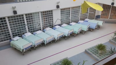 En rad tomma sjukhussängar på en öppen plats i ett sjukhus.
