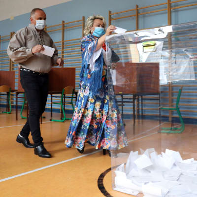 Nainen tiputtaa äänestyslipukkeen äänestysastiaan presidentinvaalin toisen kierroksen äänestyksessä Puolassa 12. heinäkuuta. 