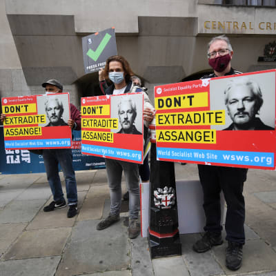Kolme mielenosoittajaa pitelee Assangen kuvalla varustettuja kylttejä.