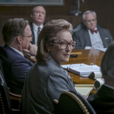 Närbild på Katharine Graham (Meryl Streep) i ett konferensrum fyllt av män.