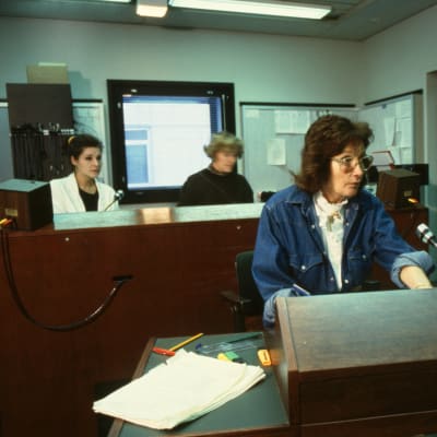 Ohjaaja Rauni Ranta ohjaa radiostudiossa, taustalla äänitarkkailijat.