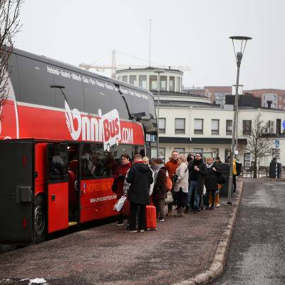 Punainen linja-auto, ihmisiä nousemassa kyytiin.
