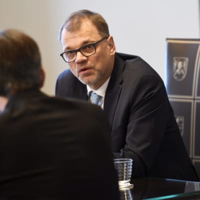 Statsminister Juha Sipilä sitter på ett möte.