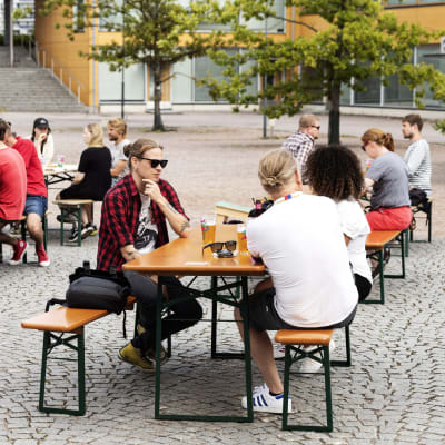 Människor sitter utomhus på en restaurangs uteservering. 