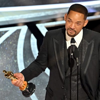 Will Smith står med sin Oscarsstatyett i handen och talar i en mikrofon.