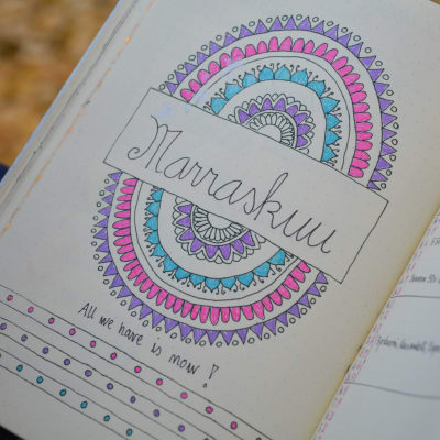 En kalender där Riikka har ritat in en färgrann Mandala symbol i lila, rosa och turkost. Hon har också skrivit in texten "All we have is now!" med svart penna.