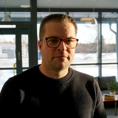 Man i svart tröja står framför ett fönster.