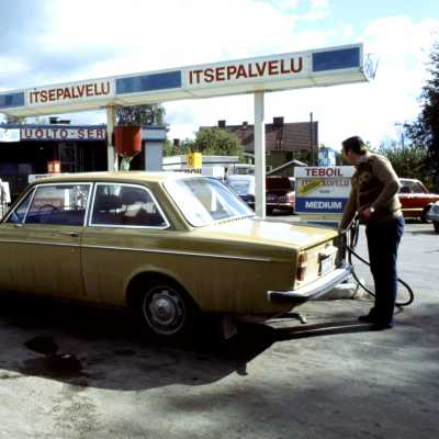 Mies tankkaa keltaista Volvo-merkkistä henkilöautoa Teboil-huoltamon pihalla. Aurinkoinen päivä.