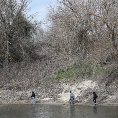 Kolme miestä kulkee Evros-joen vartta maaliskuussa 2020. 