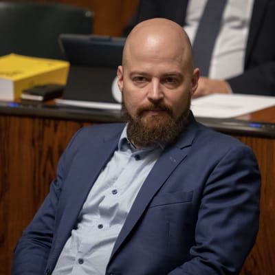 Kostymklädd man med skägg sitter i riksdagen. Centerns riksdagsledamot Mikko Kärnä i riksdagen i oktober 2019.