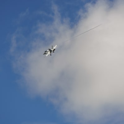 Hornet kaartaa nousun jälkeen sinistä taivasta vasten laskutelineet vielä alhaalla.
