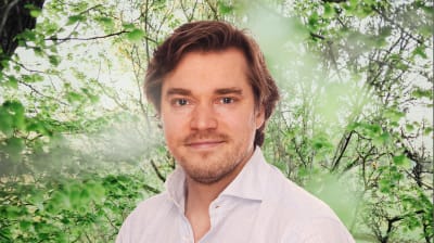 Dimitri Qvintus småler mot kameran. I bakgrunden syns en grönskande skogsdunge.