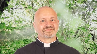 Kent Wisti småler mot kameran iklädd prästdräkt. I bakgrunden syns en grönskande bakgrund.