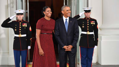 Michelle och Barack Obama står leende utanför Vita huset.